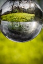 Close up view on beautiful landscape trees in blue sky and green meadow through lens ball sphere, france Royalty Free Stock Photo