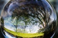 Close up view on beautiful landscape trees in blue sky and green meadow through lens ball sphere, france Royalty Free Stock Photo