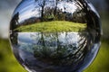 Close up view on beautiful landscape trees in blue sky and green meadow through lens ball sphere, france Royalty Free Stock Photo