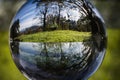 Close up view on beautiful landscape trees in blue sky and green meadow through lens ball sphere, france Royalty Free Stock Photo