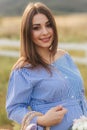 Close up view of Beautiful pregnant woman in blue dress walking hear the farm. Smile and happines