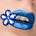 Close up view of beautiful woman lips with blue lipstick. Open mouth. Cosmetology, fashion makeup. Jewellery flower