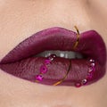 Close up view of beautiful woman lips with vinous purple matt lipstick. Cosmetology, fashion makeup. Jewellery on lips Royalty Free Stock Photo