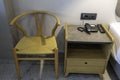 Close up view of bedside table, chair, phone and remote control. Hotel room interior design.