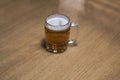 Close-up view of a beer mug filled with beer standing alone on a wooden table Royalty Free Stock Photo