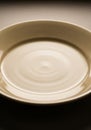 A close-up view of a beige, ceramic plate with a glossy finish. The surface shows circular rippling Royalty Free Stock Photo
