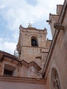 Close up view of the bell tower and gargoyles of the Santa Maria Cathedral in La Ciutadella in Menorca against a blue cloudy sky