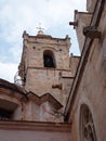 Close up view of the bell tower and gargoyles of the Santa Maria Cathedral in La Ciutadella in Menorca against a blue cloudy sky