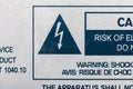 A close-up view of a bilingual warning label detailing the risk of electrical shock from a machine device or appliance, with a
