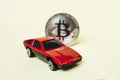 Close-up view of bitcoin and red car.