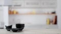 Close up view of black ceramic bowls stacked on marble table with blurred kitchen room Royalty Free Stock Photo