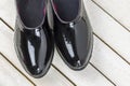 Close-up view.Black pair rubber galoshes stand on white wooden background