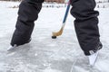 Close up view at black puck and hockey skates on lake ice, teenage male legs, rear view