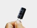 A close-up view of a black 3300uF 63V electrolytic capacitor held in a hand against a white background Royalty Free Stock Photo