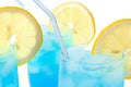 Close up view of blue lagoon cocktails with ice cubes on white