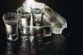 Close-up view of bottle and glasses of vodka standing isolated on black.