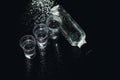 Close-up view of bottle and glasses of vodka standing isolated on black.