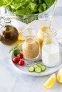 Close up view of bottles of homemade salad dressing on a tray with olive oil and butter lettuce in behind.