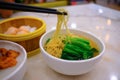 Close up view of bowl of traditional egg noodles soup with vegetables on dining table in restaurant. Dumplings in bamboo steamer Royalty Free Stock Photo