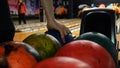 Close-up view of bowling player hand taking colorful ball from bowl lift. Media. People playing bowling - the bowling