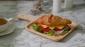 Close up view of breakfast meal with croissant sandwich ham, cheese on wooden plate and tea cup Royalty Free Stock Photo