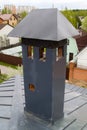 close-up view of a brick stone pipe covered with metal sheets and a black smoke box on a gray fold roof Royalty Free Stock Photo