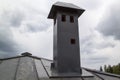 close-up view of a brick stone pipe covered with metal sheets and a black smoke box on a gray fold roof Royalty Free Stock Photo