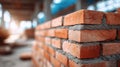 Close-up view of a brick wall under construction, showcasing textured red bricks and mortar, with a blurred background of a Royalty Free Stock Photo