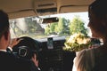 Close up view bride and groom inside car drive to wedding party to meet friends outdoors . Wedding couple celebrates marriage in