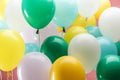 Close up view of bright green, white, yellow and blue decorative balloons on pink background. Royalty Free Stock Photo