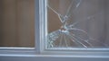 Close-up view of a broken window pane showing radial glass cracks and frame detail Royalty Free Stock Photo