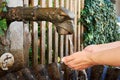 A close-up view of a bronze fountain with running water in Salzburg and a drinking woman washing her hands - Austria