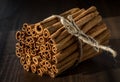 Close up view of a bundle of cinnamon sticks tied with twine against a dark background.