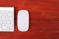 Close up view of a business workplace with wireless computer keyboard keys and mouse on old red natural wooden table background. Royalty Free Stock Photo