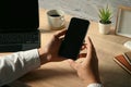 Close up view of businessman hands holding smart phone while sitting front of laptop at working desk Royalty Free Stock Photo