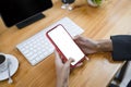 Businesswoman holding mock up mobile phone with lank screen at her workspace. Royalty Free Stock Photo