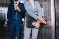 Close-up view of businesswoman pushing button in elevator by man in earphones Royalty Free Stock Photo