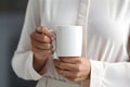 Close-up view of a businesswoman\'s hand grasping a coffee mug in a well-lit break room. AI Generated