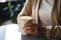 Close-up view of a businesswoman\'s hand grasping a coffee mug in a well-lit break room. AI Generated
