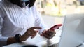 Businesswoman sitting in front of laptop computer and using mobile phone at her workspace. Royalty Free Stock Photo