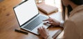 Close-up view of businesswoman working on her project while typing on blank screen laptop computer Royalty Free Stock Photo