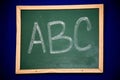Close-up view of a chalkboard with a stylized ABC written in white chalk on the blackboard surface