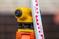 close-up view of cheap geodesy level device with tower ruler outdoors Royalty Free Stock Photo