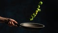 Close-up view of chef hand with pan throws mix of frying brussels sprout on dark blue background. Frozen motion. Backstage of