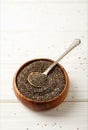 close up view of chia seeds and spoon in wooden bowl on white surface Royalty Free Stock Photo