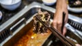 The close up view of chopstick holding a slice of cooked meat after dip into the boiling soup