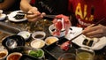 The close up view of chopstick holding a slice of raw meat before dip into the boiling soup