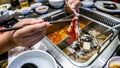 The close up view of chopstick holding a slice of raw meat before dip into the boiling soup