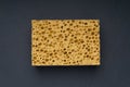 Close up view of cleaning sponge, mesh structure pattern on black surface. Yellow sponge close-up. Royalty Free Stock Photo