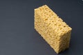Close up view of cleaning sponge, mesh structure pattern on black surface. Yellow sponge close-up. Royalty Free Stock Photo